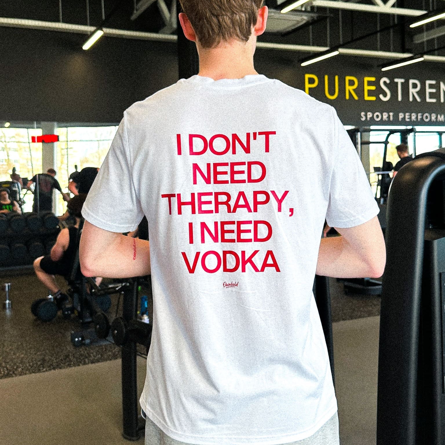 Person wearing a white t-shirt with red text in an indoor setting