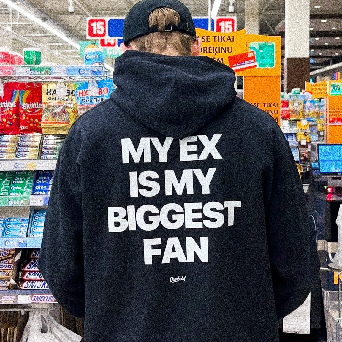 Person wearing a black hoodie with text in a grocery store