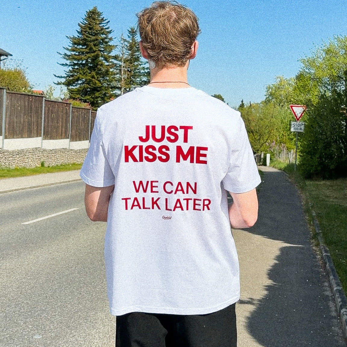 Person wearing a white t-shirt with red text on a road