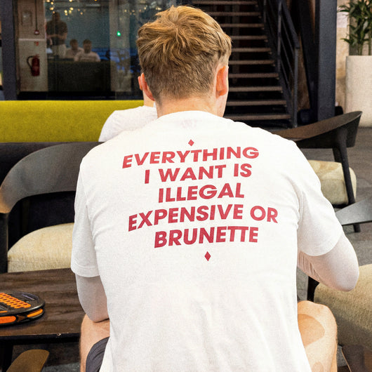 Person wearing a white t-shirt with red text in an indoor setting
