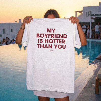 Person holding a t-shirt with text by a poolside at sunset