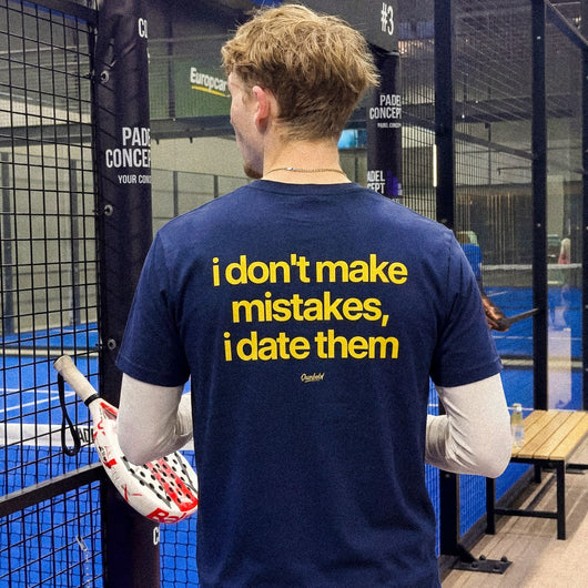 Person wearing a blue t-shirt with humorous text in an indoor sports facility.